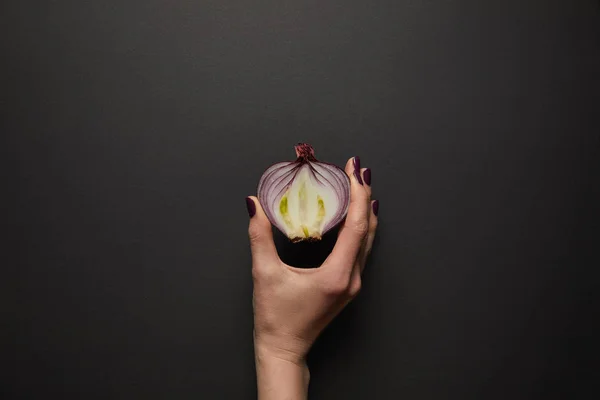 Teilansicht einer Frau mit geschnittener Zwiebel auf schwarzer Oberfläche — Stockfoto
