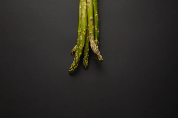 Top view of fresh green asparagus on black surface — Stock Photo