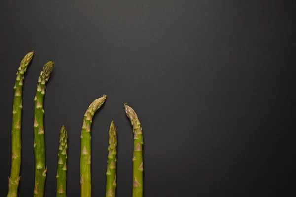 Top view of fresh green asparagus on black surface — Stock Photo