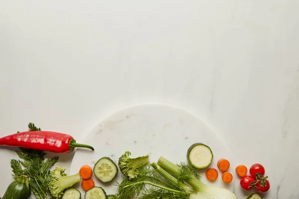 Vista superior de verduras enteras y cortadas en superficie blanca - foto de stock