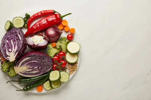 Vista superior de verduras enteras y cortadas en superficie blanca - foto de stock