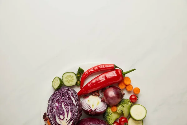 Вид сверху свежих срезанных и целых овощей на белую поверхность — стоковое фото