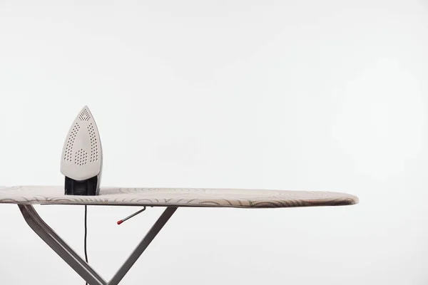 Ironing board with dark legs and iron isolated on grey — Stock Photo