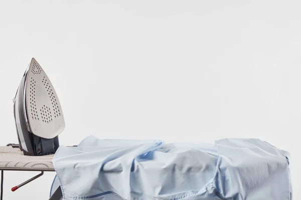 Camisa de hierro y azul sobre tabla de planchar aislada sobre blanco - foto de stock