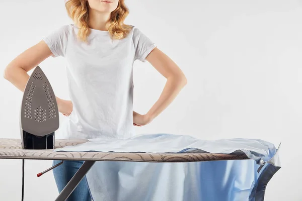 Partial view of woman standing with arms akimbo near ironing board isolated on grey — Stock Photo