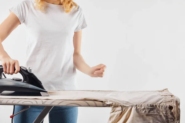 Teilansicht einer Frau, die braune Hosen auf Weiß bügelt — Stockfoto