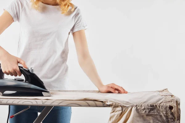 Vista parcial de la mujer planchando pantalones marrones aislados en blanco - foto de stock