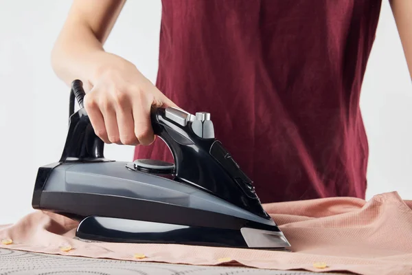 Cropped view of woman with black iron ironing shirt isolated on grey — Stock Photo