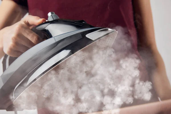 Cropped view of young woman holding steaming iron in hand — Stock Photo