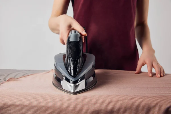 Partial view of young woman ironing clothes with iron — Stock Photo