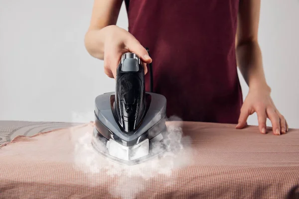 Partial view of young woman ironing clothes with iron — Stock Photo