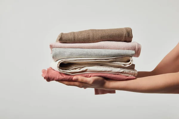 Vista recortada de la mujer sosteniendo ropa de plancha plegada aislada en gris - foto de stock