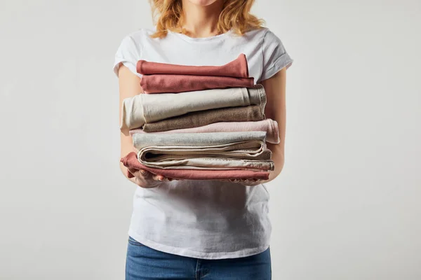 Обрізаний вид жінки, що тримає складений випраний одяг ізольований на сірому — стокове фото