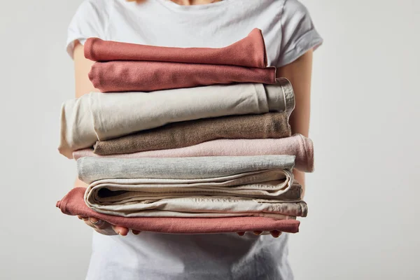 Cropped view of woman holding folded ironed clothes isolated on grey — Stock Photo