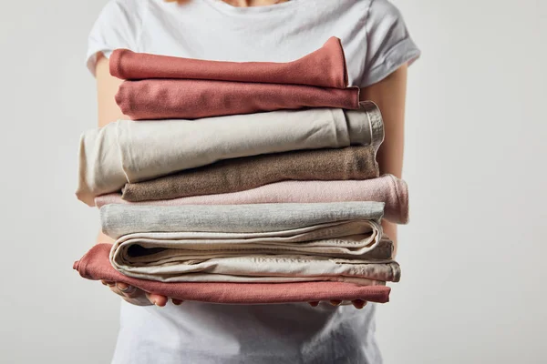 Vista recortada de la mujer sosteniendo ropa de plancha plegada aislada en gris - foto de stock