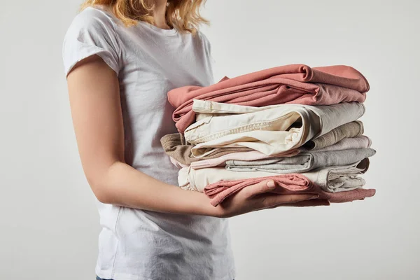 Vista ritagliata della donna che tiene vestiti piegati stirati isolati sul grigio — Foto stock