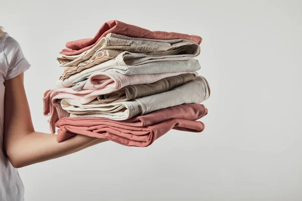 Vista cortada da mulher segurando roupas passadas dobradas isoladas em cinza — Fotografia de Stock