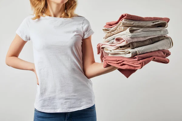 Cropped view of woman holding folded ironed clothes isolated on grey — Stock Photo