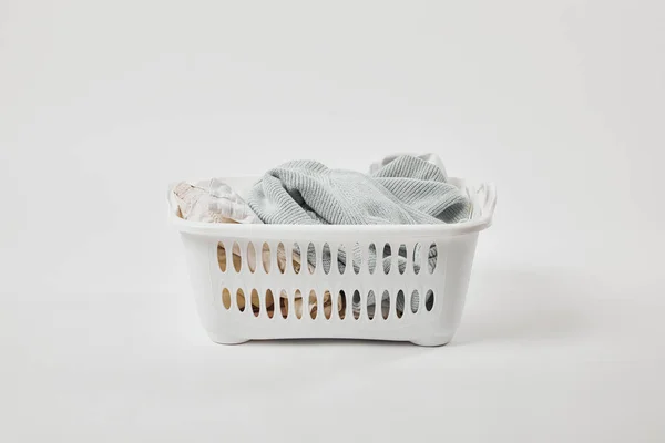 Panier à linge en plastique blanc avec vêtements sales sur gris — Photo de stock