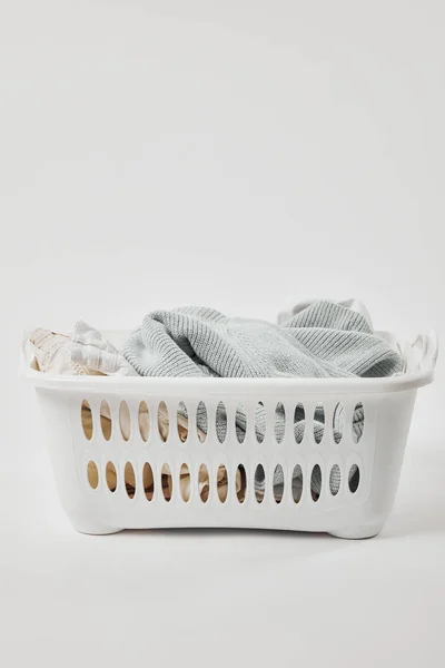 White plastic laundry basket with dirty clothes on grey — Stock Photo