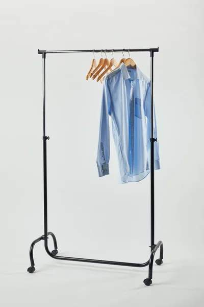 Scaffale dritto, appendini in legno e camicia blu isolata su grigio — Foto stock