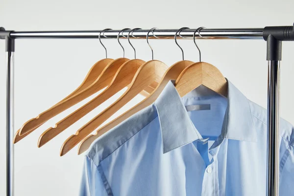 Perchero recto, perchas de madera y camisa azul aislados en gris - foto de stock