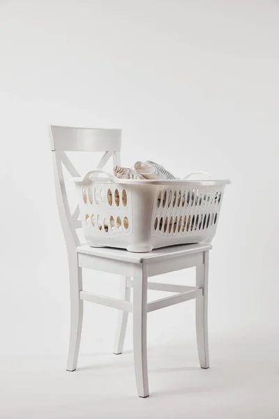 Wooden chair with plastic laundry basket on white — Stock Photo