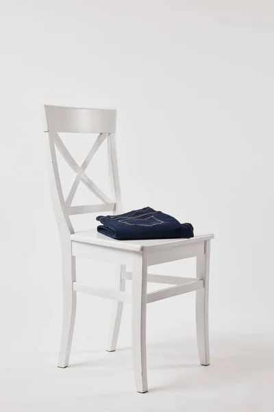 Wooden chair with folded denim pants on white — Stock Photo