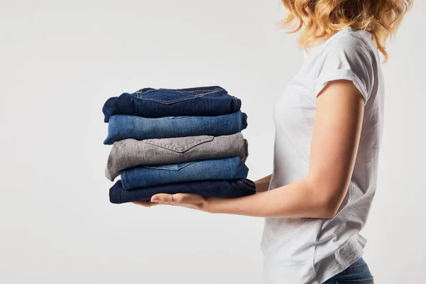 Vista recortada de niña sosteniendo pantalones planchados aislados en blanco - foto de stock