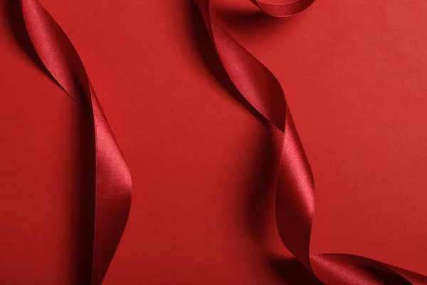Close up of curved silk red ribbons on red background — Stock Photo