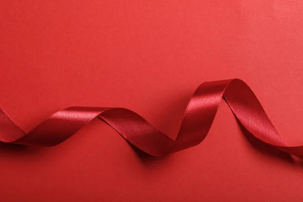 Vista superior da fita vermelha de seda ondulada no fundo vermelho com espaço de cópia — Fotografia de Stock