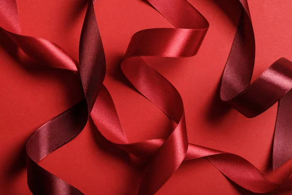 Gros plan de rubans bordeaux et rouges en soie sur fond rouge — Photo de stock