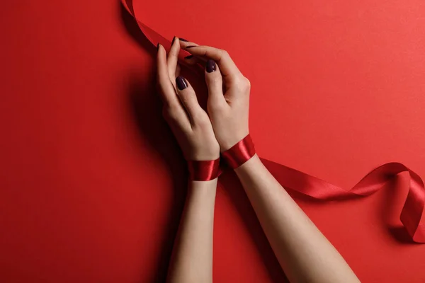 Draufsicht der Frau gebunden mit Satinband auf rotem Hintergrund — Stockfoto