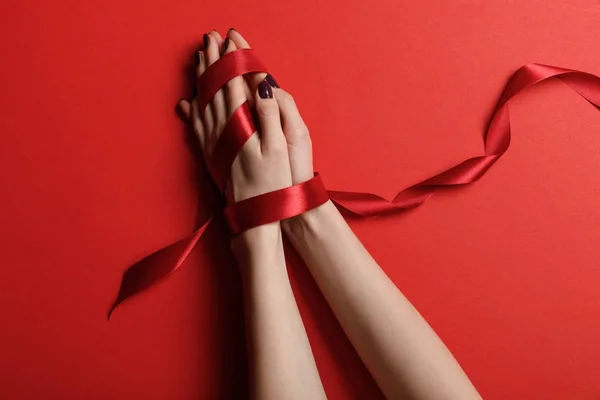 Partial view of woman tied with silk ribbon on red background — Stock Photo