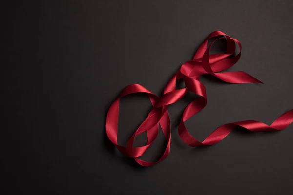 Top view of red satin ribbon on black background with copy space — Stock Photo