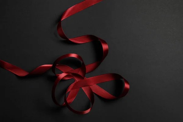 Top view of red satin wavy ribbon on black background with copy space — Stock Photo