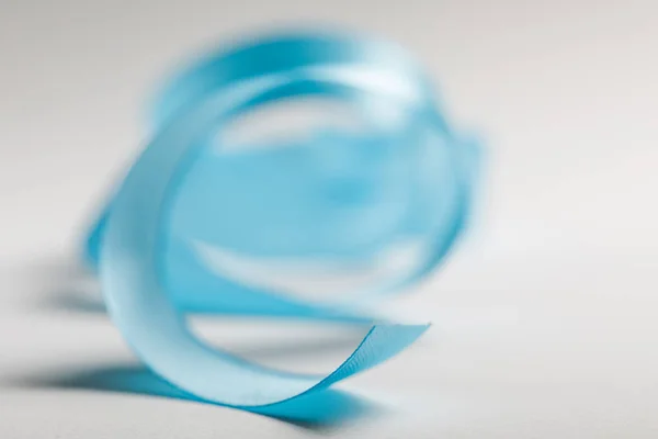 Селективный фокус изогнутой синей атласной ленты на сером фоне — стоковое фото