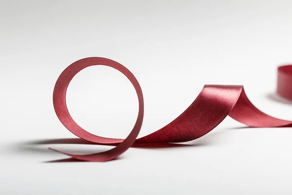 Silk curved burgundy ribbon on grey background — Stock Photo