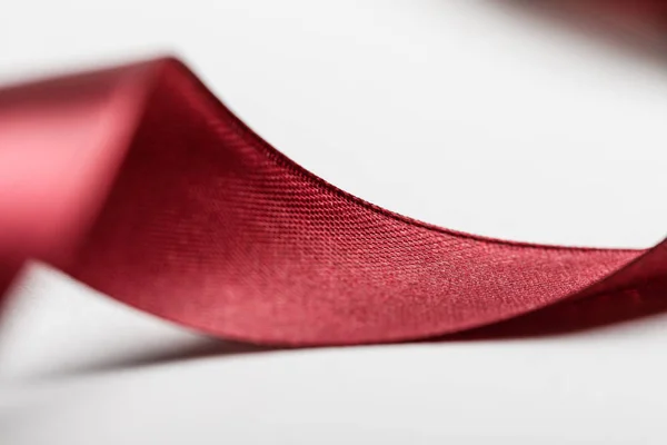 Close up of shiny silk curved burgundy ribbon on grey background — Stock Photo