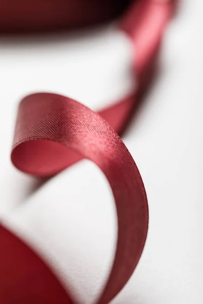 Close up of silk wavy burgundy ribbon on grey background — Stock Photo