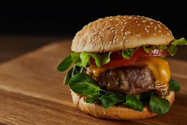 Close up of tasty meat burger on wooden chopping board — Stock Photo
