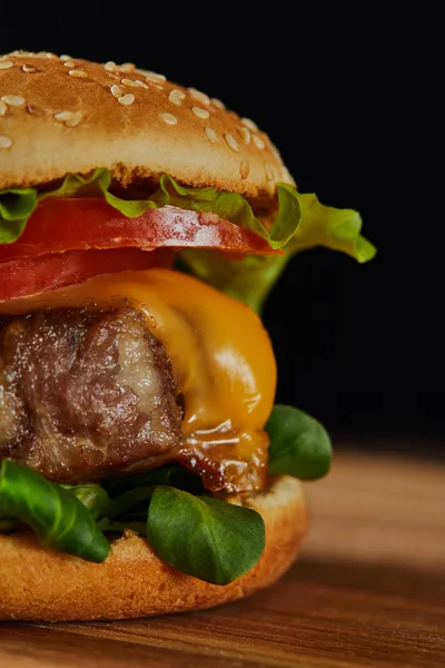 Primer plano de deliciosa hamburguesa de carne con queso, verdor, tomates y sésamo - foto de stock