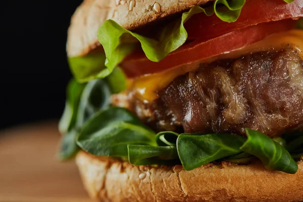Close up of tasty meat burger with cheese, greenery and tomatoes — Stock Photo