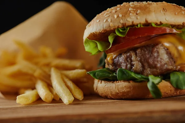 Messa a fuoco selettiva di deliziosi hamburger con carne e patatine fritte sulla superficie di legno — Foto stock