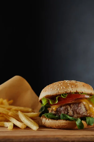 Selective focus of tasty burger with meat and french fries on black background — Stock Photo