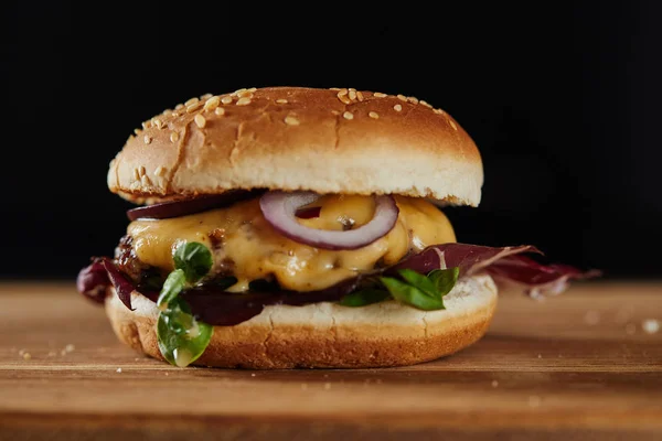 Hambúrguer delicioso com carne, queijo e cebolas isoladas em preto — Fotografia de Stock