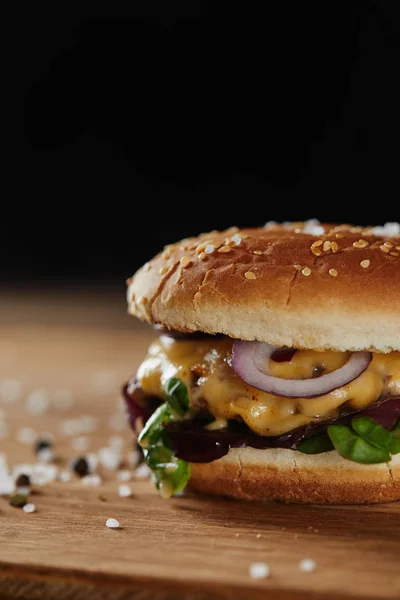 Condimento y deliciosa hamburguesa con carne, queso y cebolla aislados en negro - foto de stock