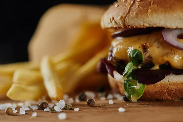 Fuoco selettivo di sale e gustoso hamburger con carne e formaggio sulla superficie di legno — Foto stock