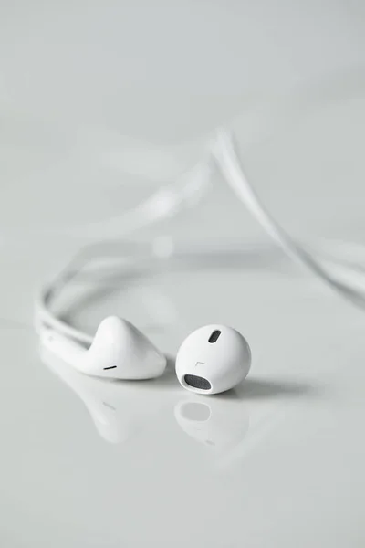 Selective focus of white wired earphones on white surface with copy space — Stock Photo