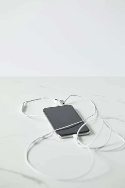 Selective focus of smartphone with blank screen and earphones isolated on grey — Stock Photo